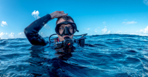 nervous looking scuba diver with hand on top of head signaling ok